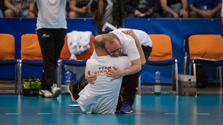 Foto CEV: Europameister-Trainer Matus Kalny (sitzend) wird nach dem EM-Matchball von seinem Co-Trainer Olaf Minter umarmt