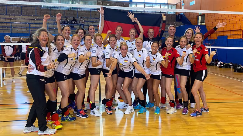 Mallorca war die Reise wert: Im Endspiel der Altersgruppe 34-44 schlugen die deutschen Ü40-Frauen das Team aus Bulgarien in zwei Gewinnsätzen (25:12, 25:11). Unter der Leitung von Renate Riek-Bauer (li.) und Co-Trainerin Christina Benecke (hi.re. m.Fahne) trumpften unter anderem ehemalige Beach- und Hallennationalspielerinnen wie Antje Fröhlich-Röder, Tanja Hart-Schneider, Martina Stoof und Johanna Thewes (geb. Reinink) auf. Die Münchnerin Michaela Henry, geb. Eckl (hi.li.), wurde zur besten Hallenspielerin der EM gewählt.